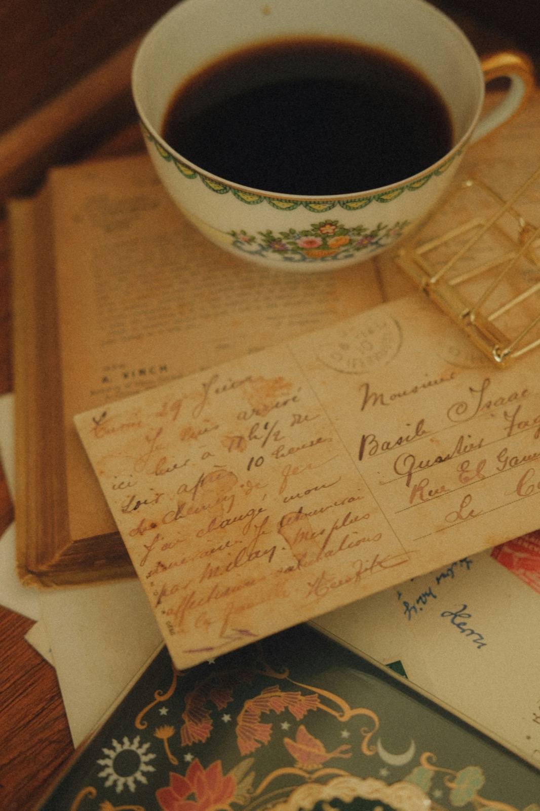 a cup of coffee resting on a stack of old handwritten postcards